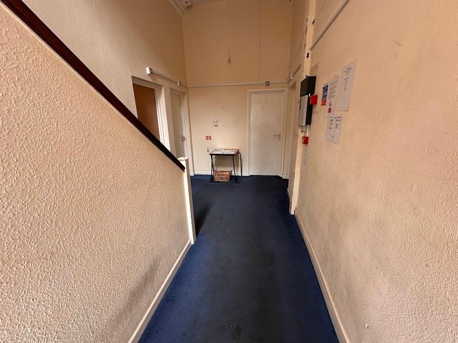 A simple hallway with a blue carpet and cream w...