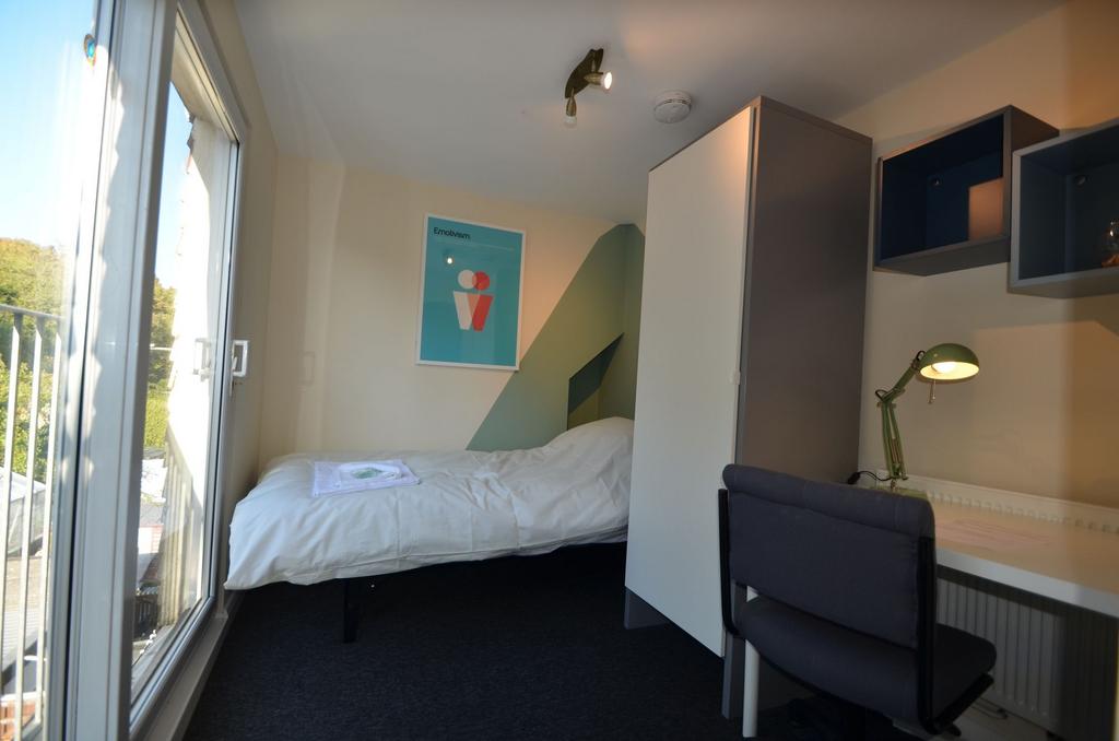 A cozy and well-lit single bedroom featuring a ...