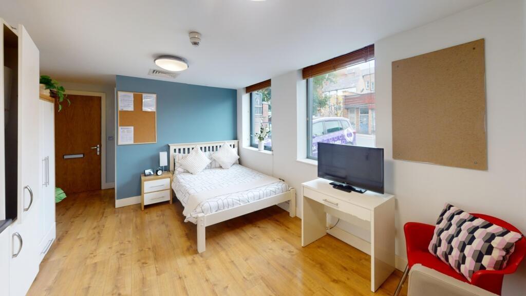 A spacious and bright bedroom featuring a comfo...