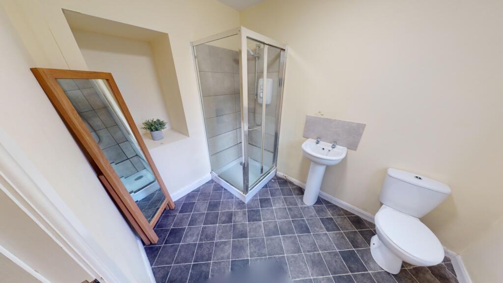 Bright and clean bathroom featuring a corner gl...