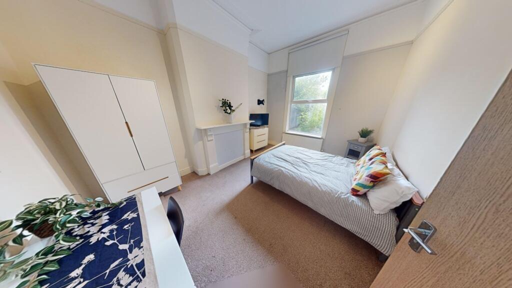 A clean and cozy single bedroom featuring a com...