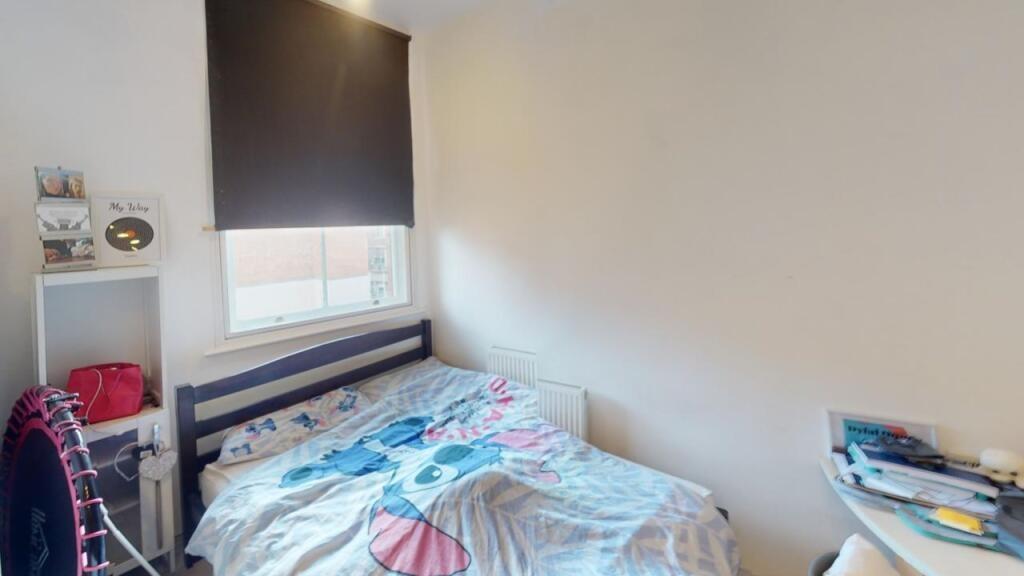 A cozy single bedroom featuring a neatly made b...