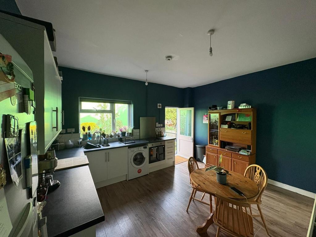 A cozy kitchen with dark teal walls, modern whi...