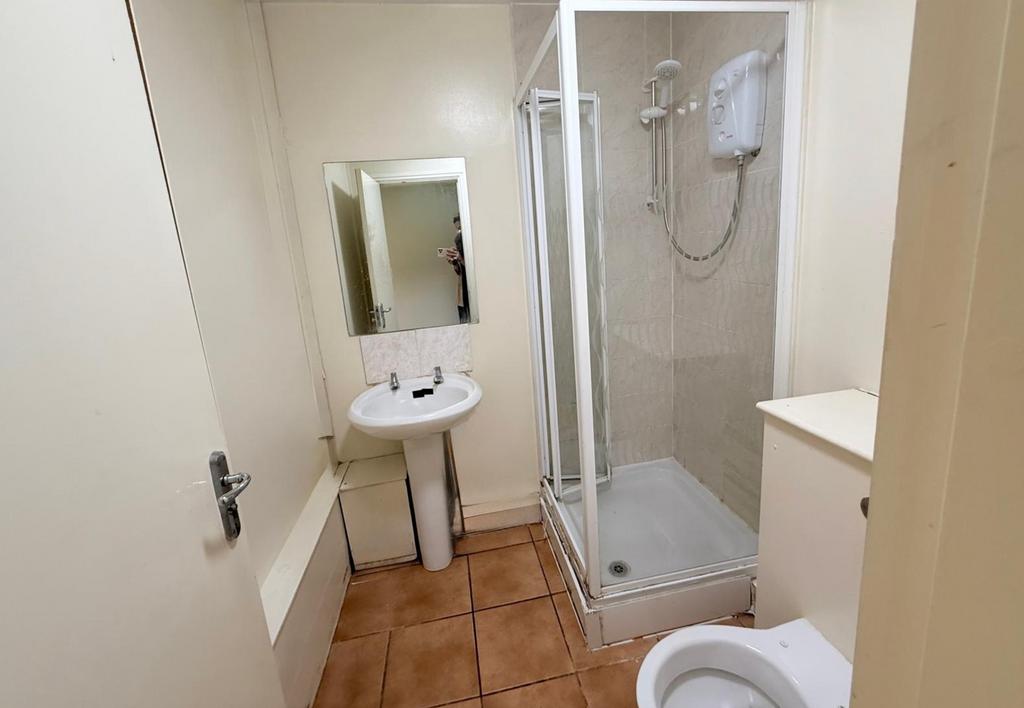 A compact bathroom featuring a shower enclosure...