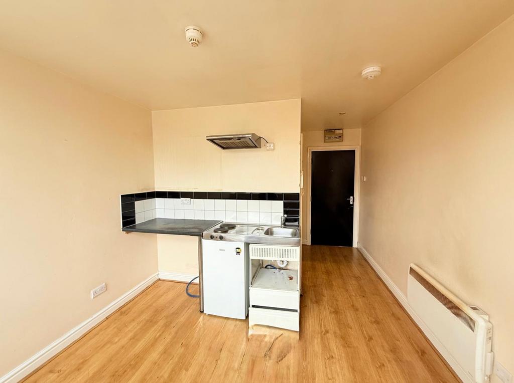Compact kitchen area featuring a small fridge, ...