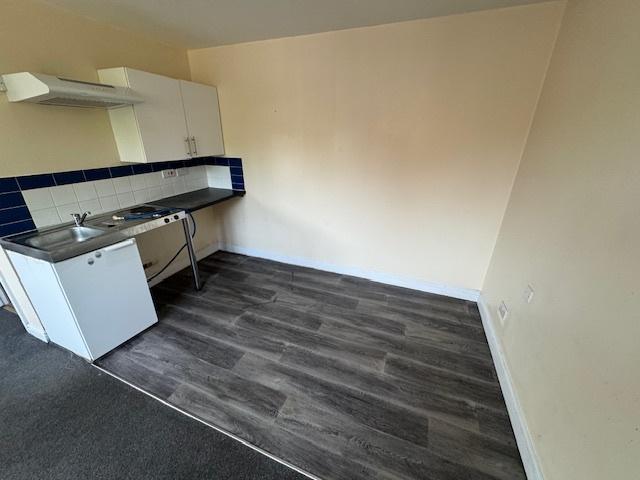 A compact kitchen area featuring basic white ca...
