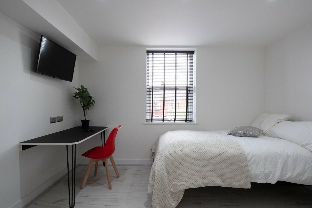 A bright and tidy student bedroom featuring a c...