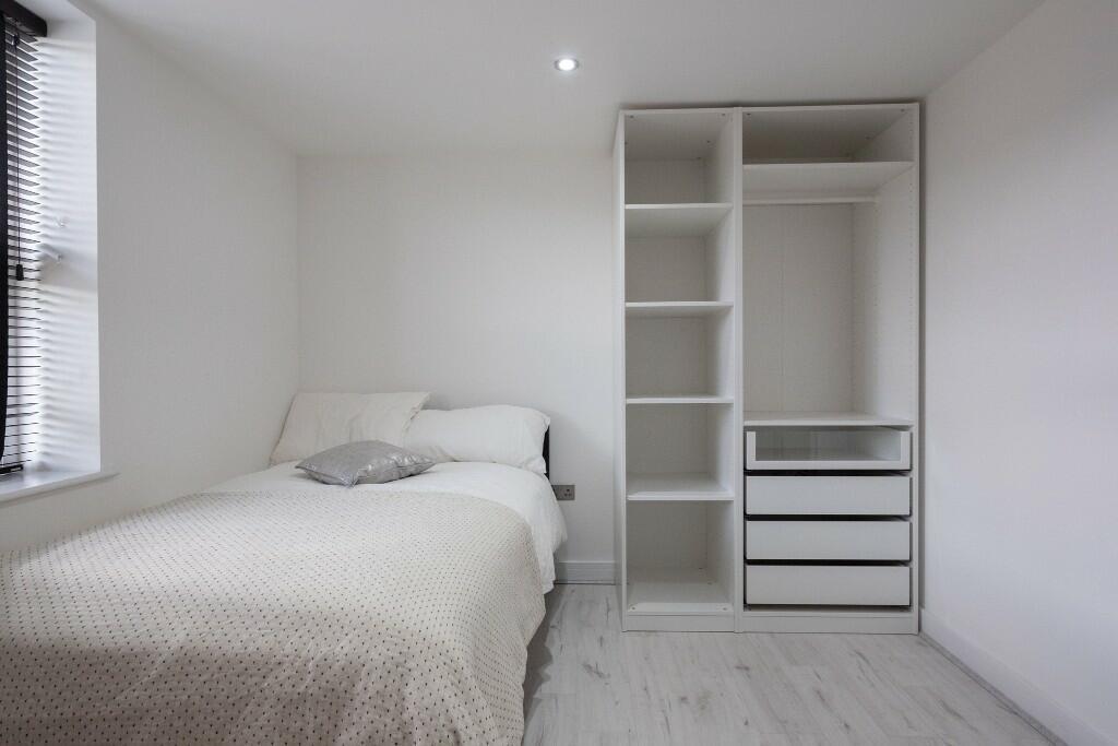 A clean and bright bedroom featuring a comforta...