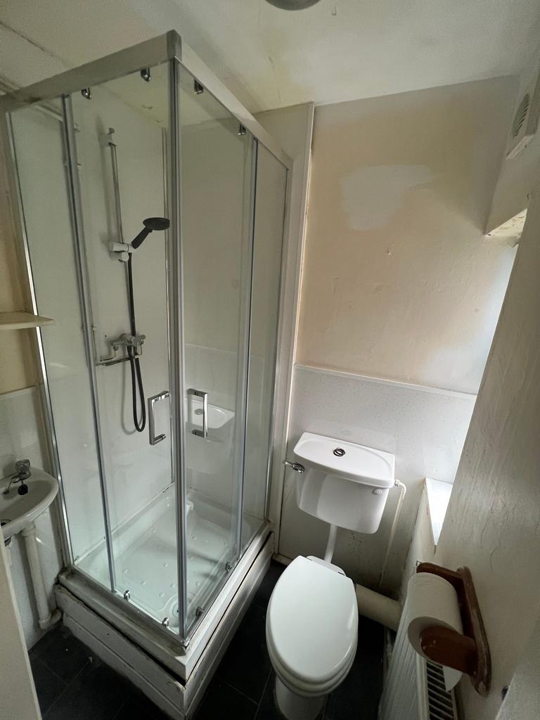 Compact bathroom featuring a modern shower encl...