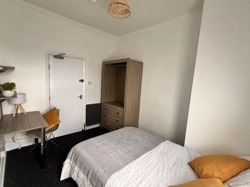 A cozy single bedroom featuring a comfortable b...
