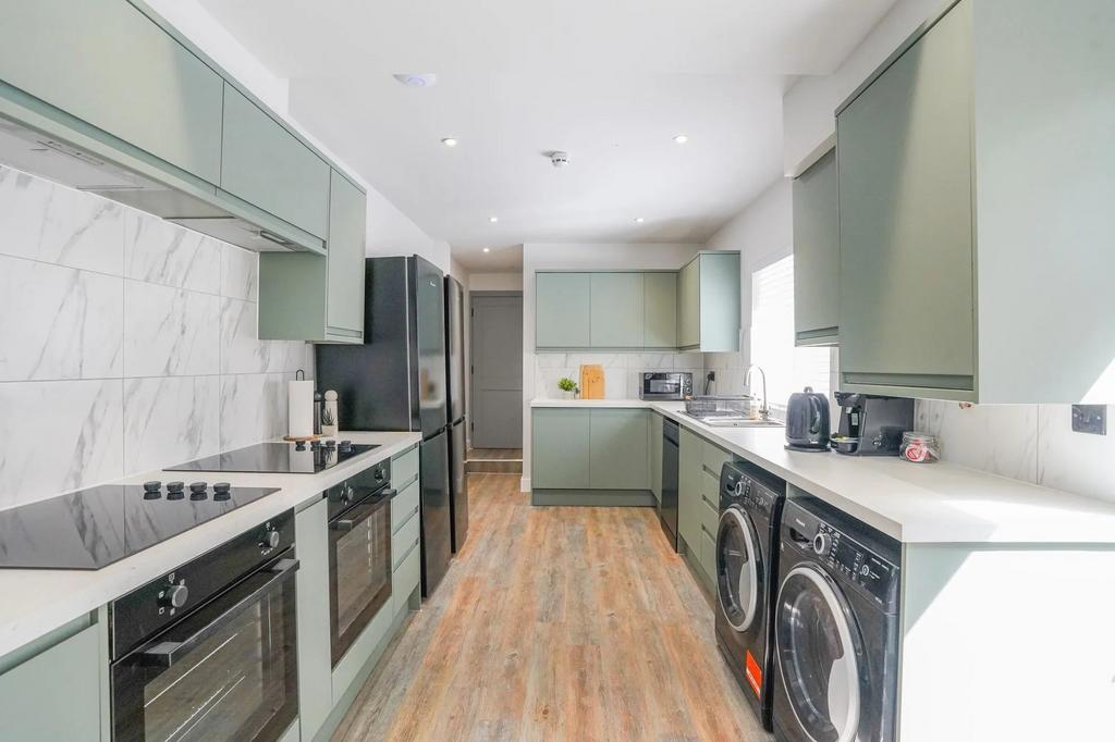 Modern kitchen featuring sage green cabinets, a...