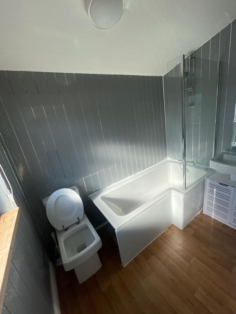 A modern bathroom suite with a white corner bat...