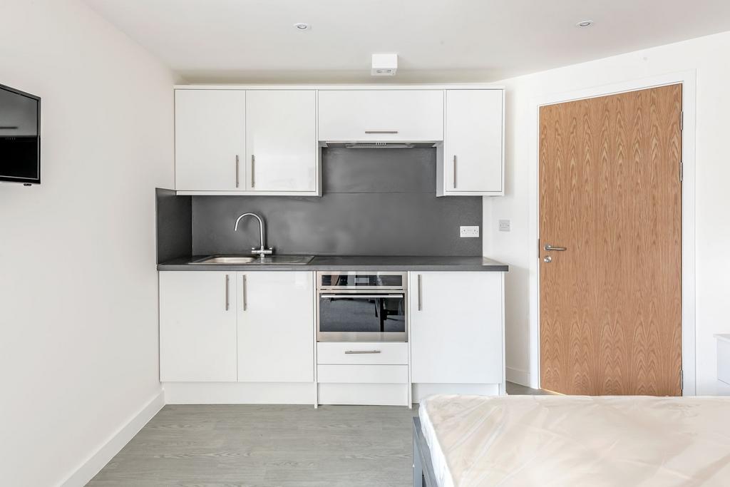 A modern, compact kitchen featuring sleek white...