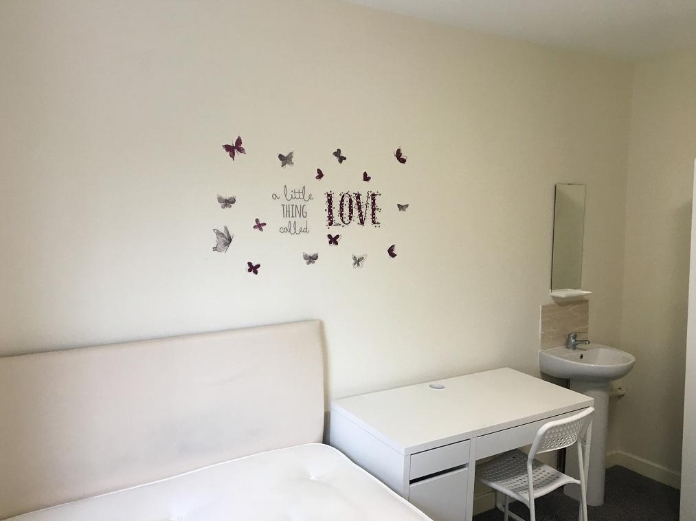 A simple, tidy single bedroom featuring a white...