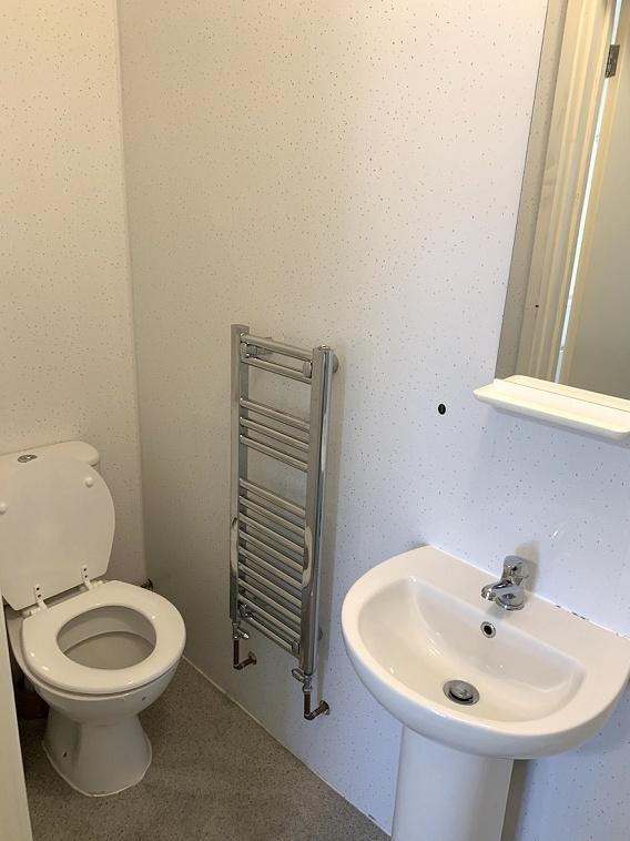 A clean and simple single toilet room featuring...