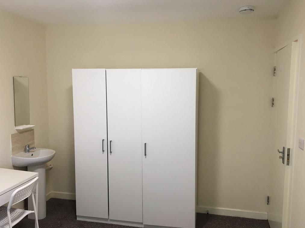 A neat and simple single bedroom featuring a wh...
