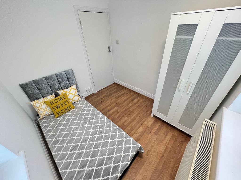 A neat and tidy single bedroom featuring a comf...