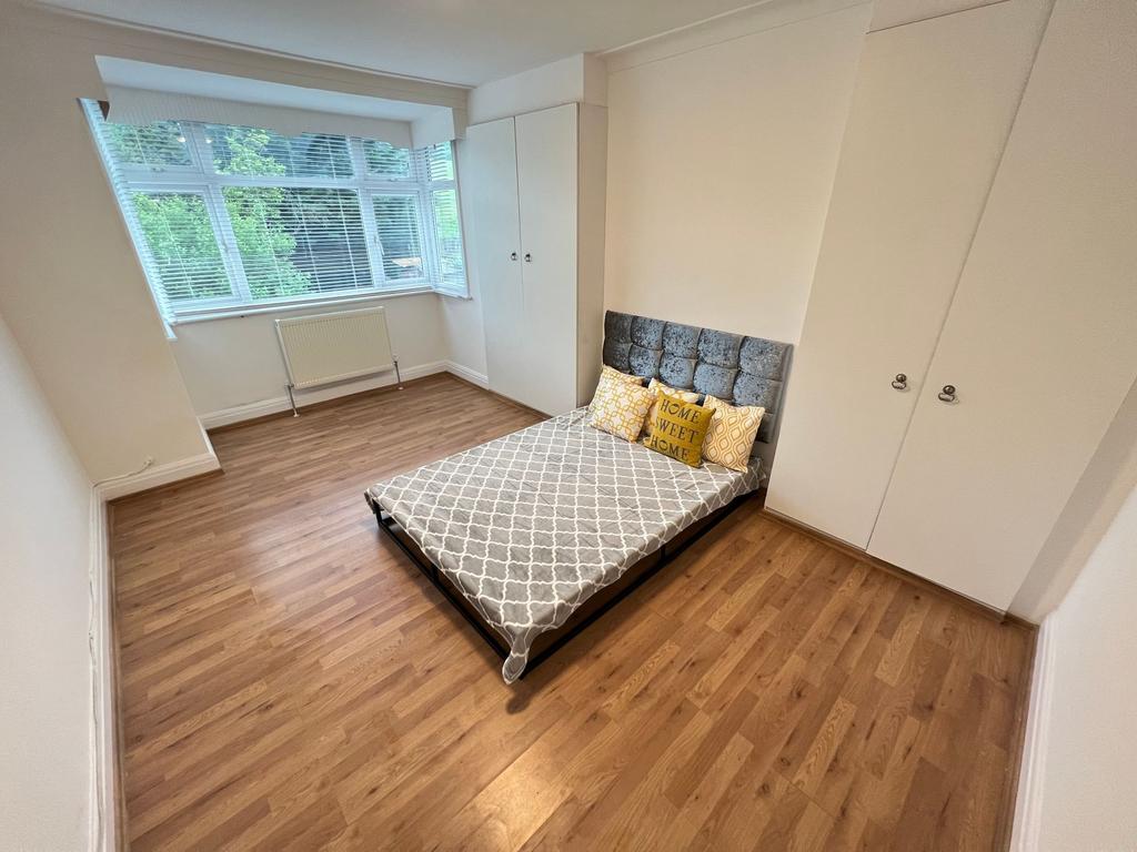 A bright double bedroom featuring a comfortable...