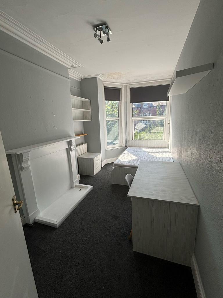 A cozy single bedroom featuring a large window ...