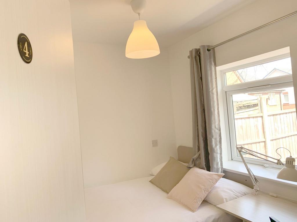 A cozy and tidy single bedroom featuring a comf...