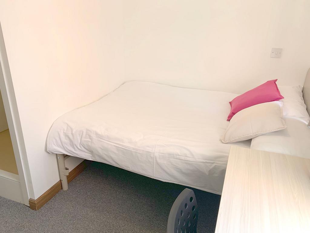 A neat and tidy single bedroom featuring a simp...