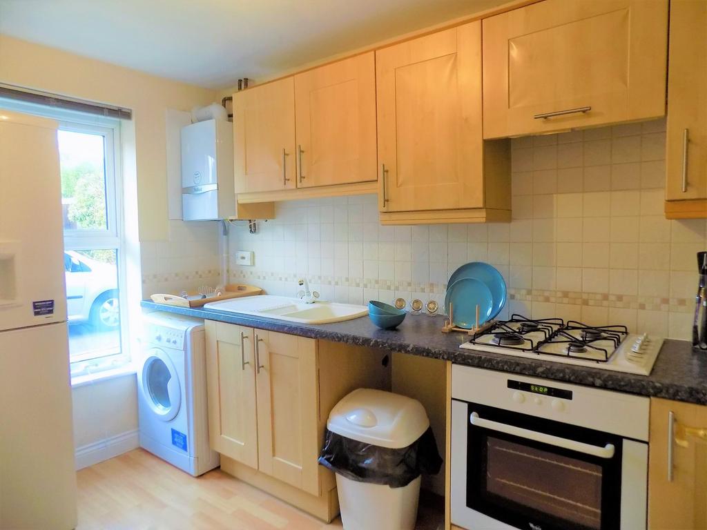 Bright and tidy kitchen featuring light wood ca...