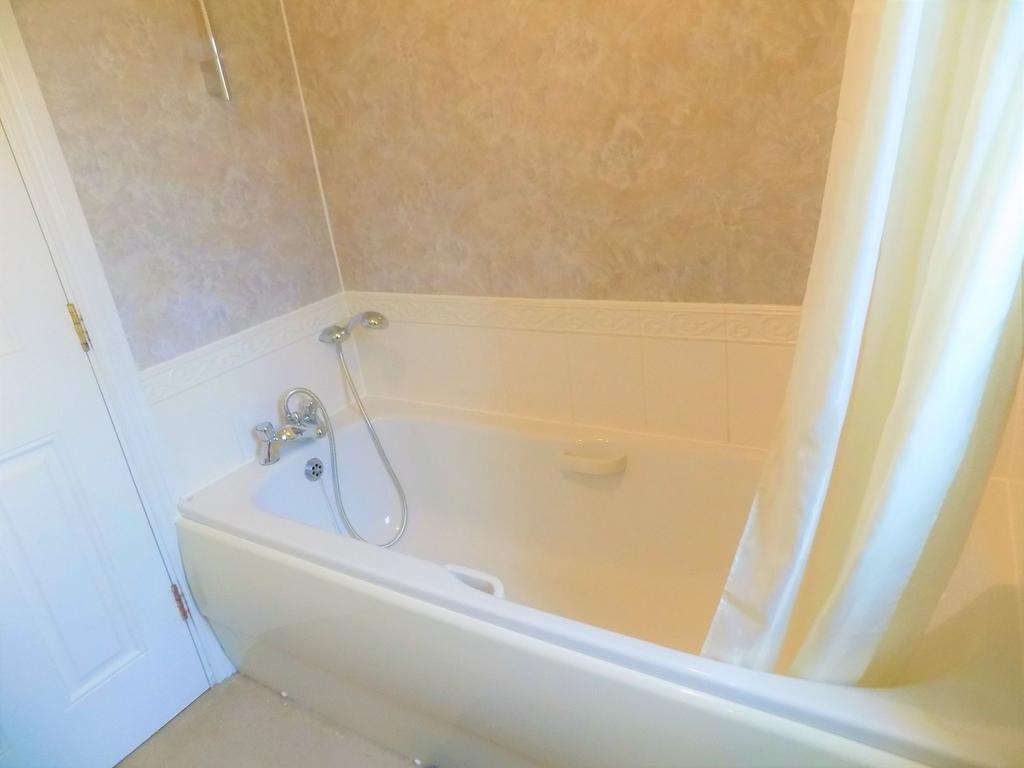 A bright and clean bathroom suite featuring a s...