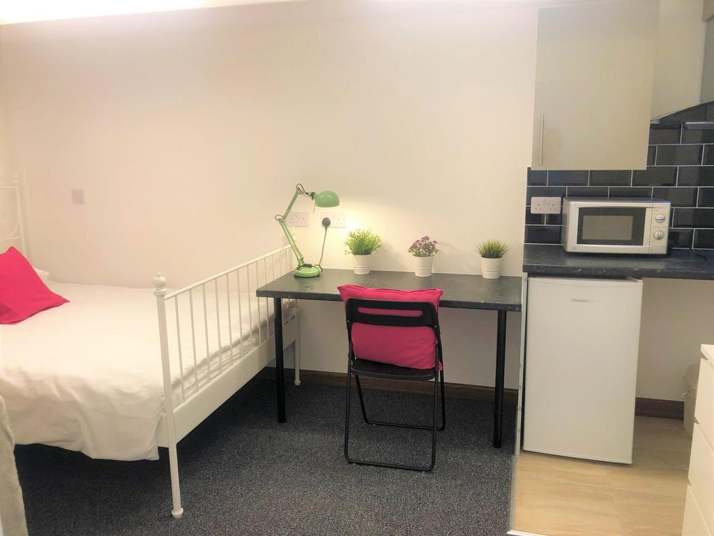 A neat and tidy single bedroom featuring a whit...