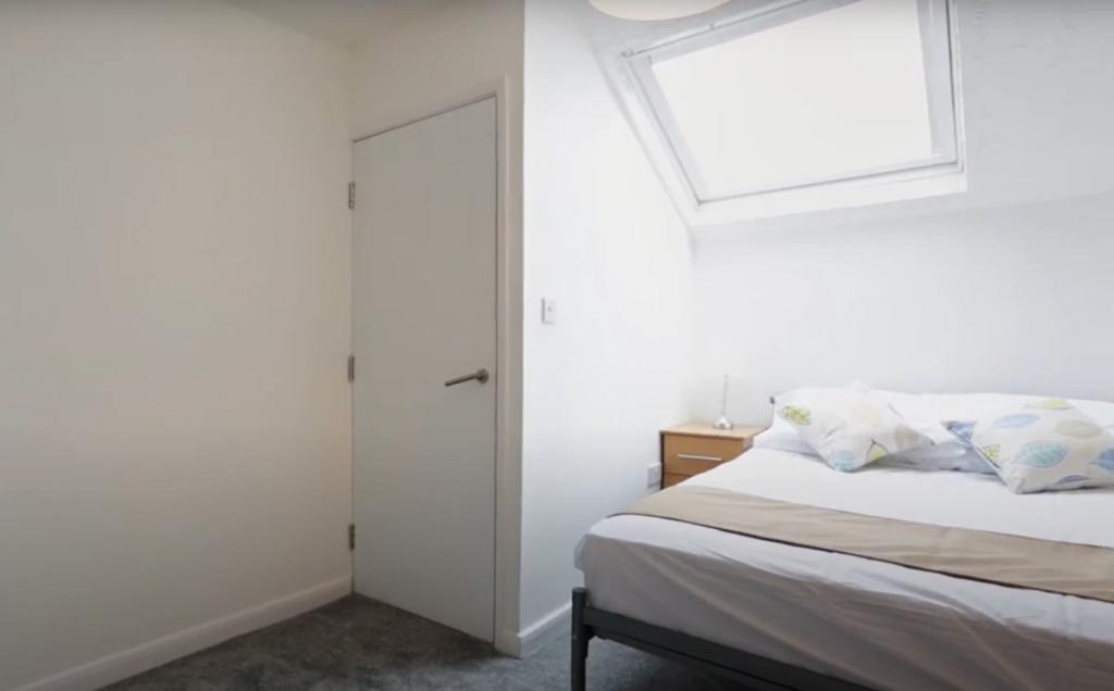Bright and clean small bedroom featuring a skyl...
