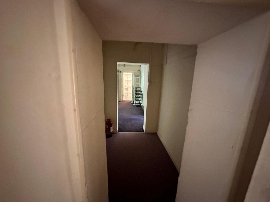 A spacious hallway leading to various rooms, of...