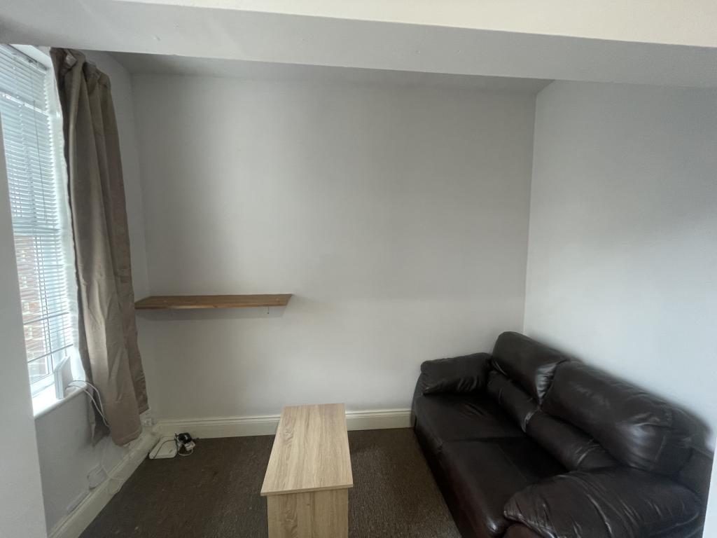 A compact living room featuring a dark leather ...