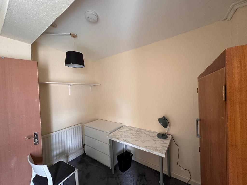 Compact furnished single bedroom with a desk, c...