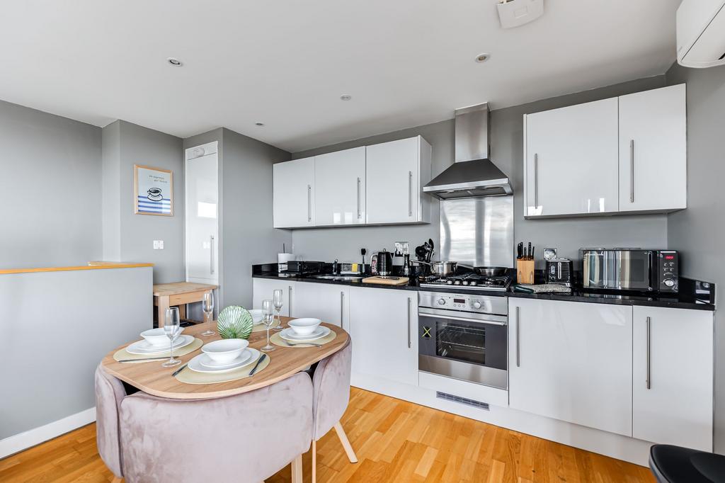 A modern kitchen featuring sleek white cabinets...