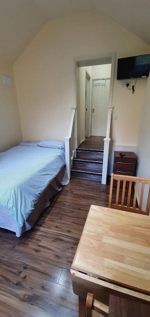 A cozy single bedroom with wooden flooring, a n...