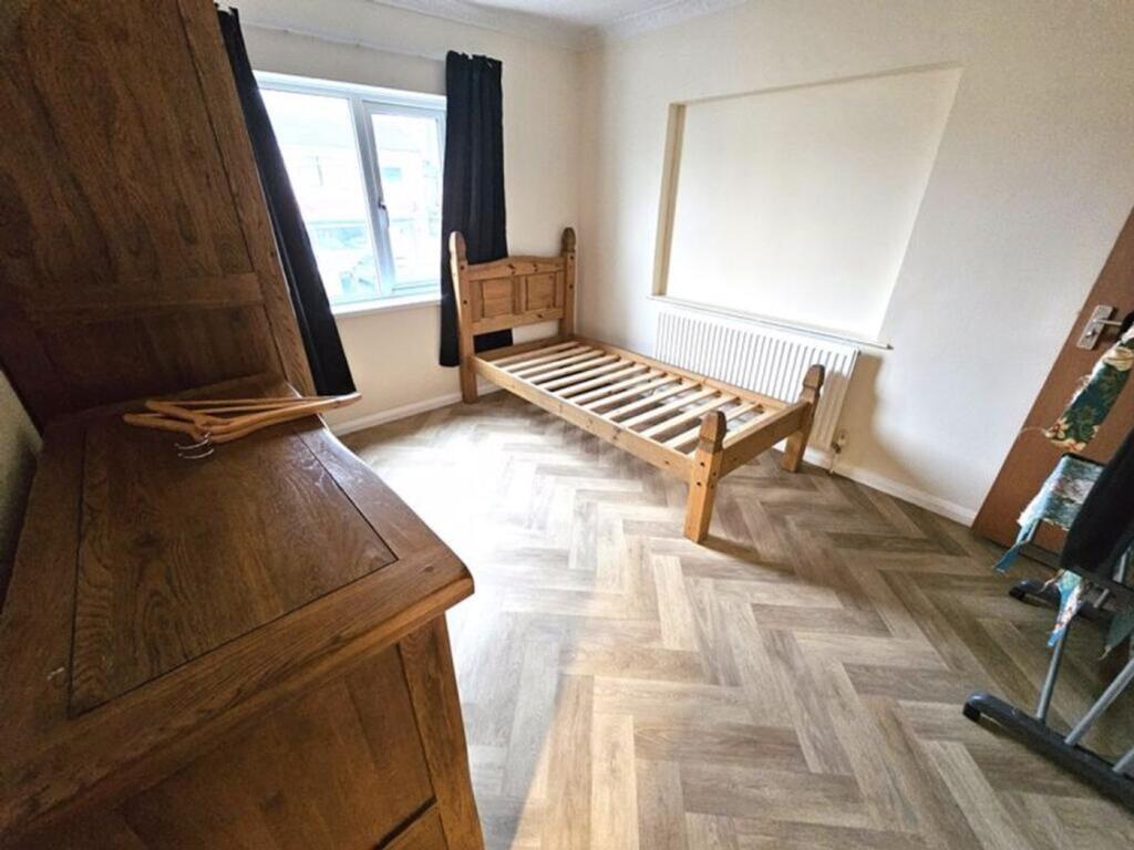 A tidy single bedroom featuring a wooden bed fr...