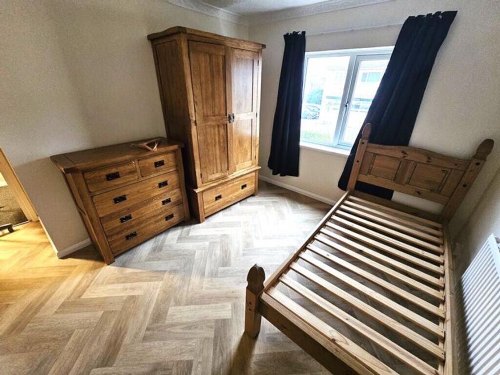 A tidy, well-lit bedroom featuring wooden furni...