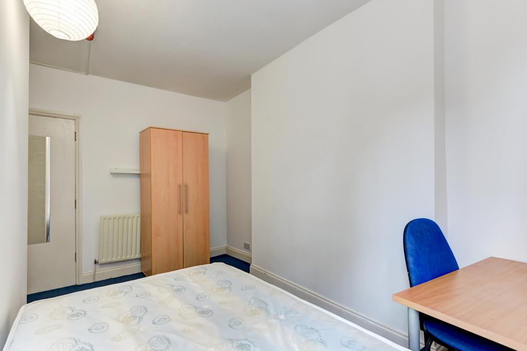 A cozy single bedroom featuring a bed with a si...