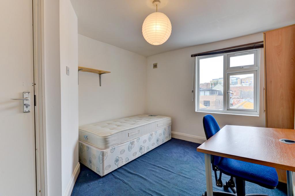 A tidy and well-lit student bedroom featuring a...