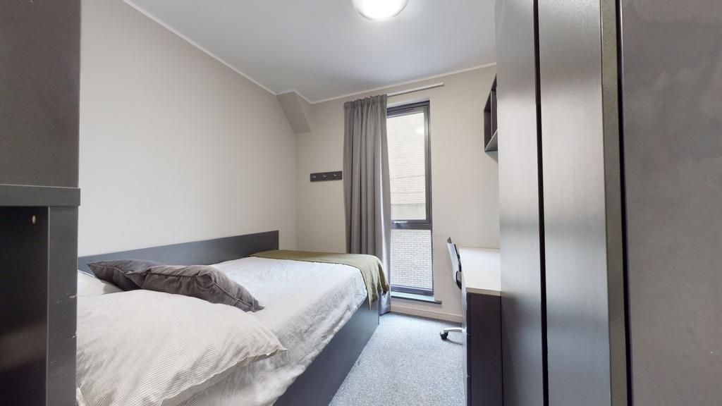 A compact, well-maintained bedroom illuminated ...