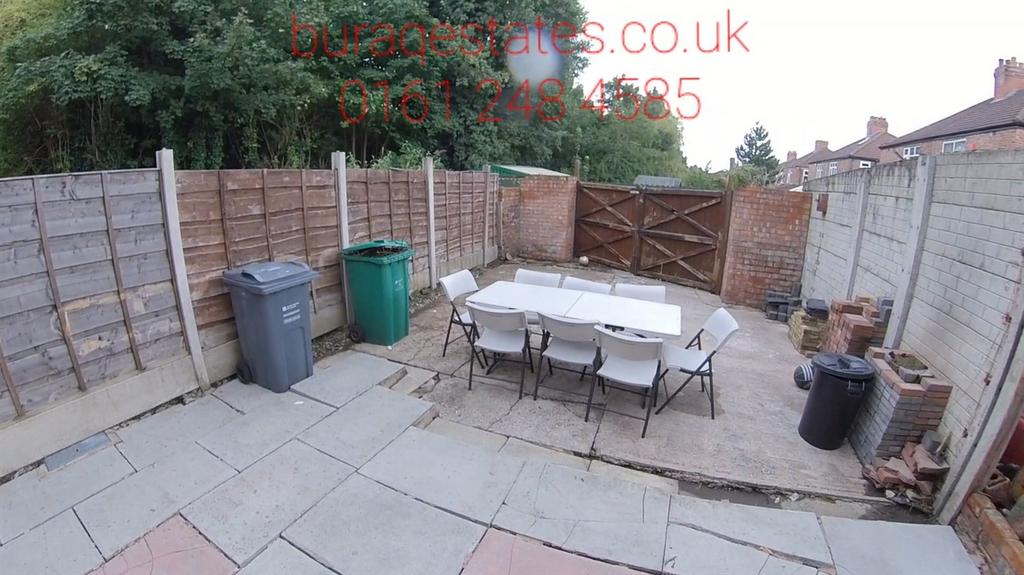 Paved rear garden with a central outdoor dining...