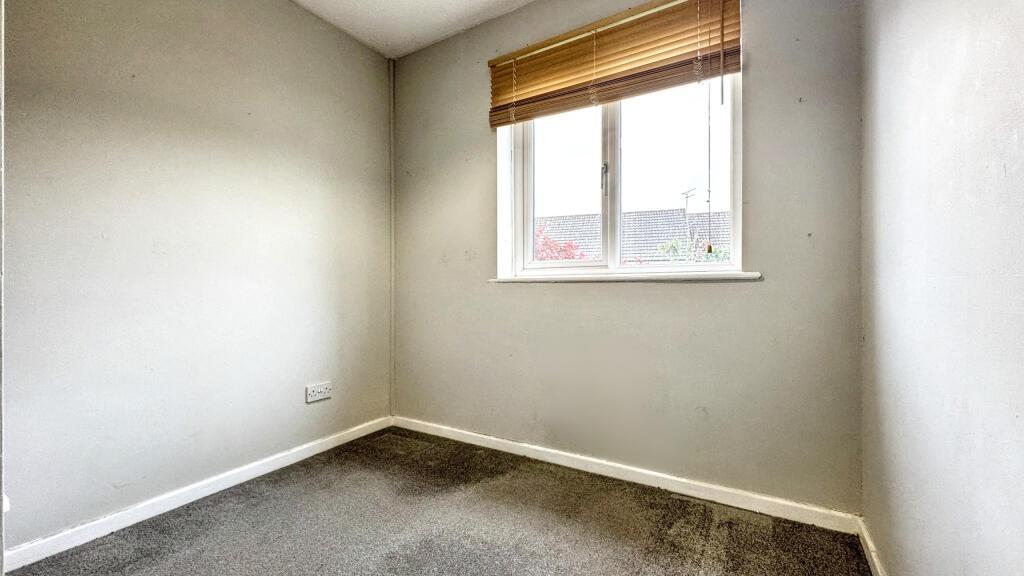 A small, neutral-colored room with a single win...