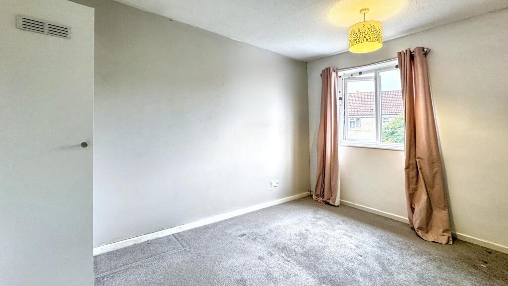 A bright double bedroom featuring a large windo...