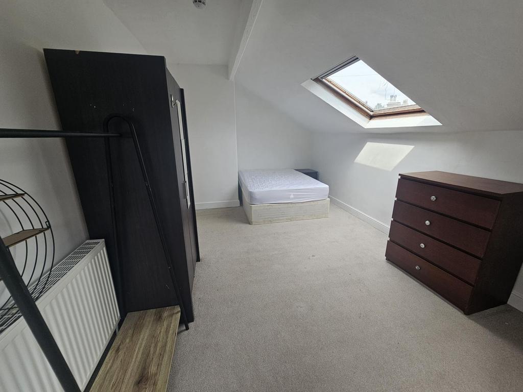 A cozy bedroom with a sloped ceiling and a skyl...