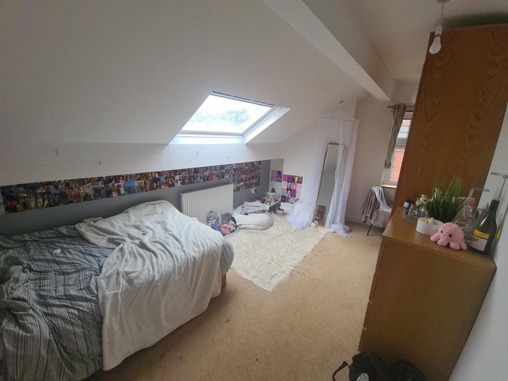 A cozy single bedroom featuring a sloped ceilin...
