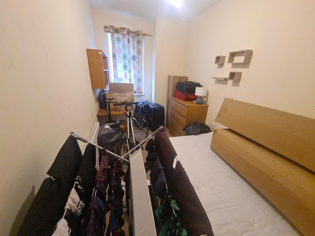 A compact bedroom featuring a single bed with l...