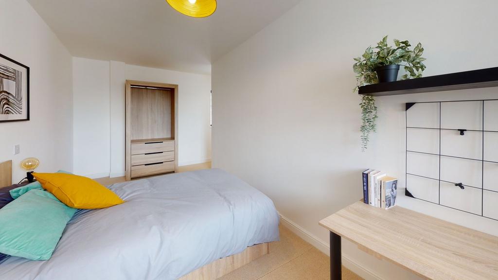 A bright and tidy bedroom featuring a neatly ma...