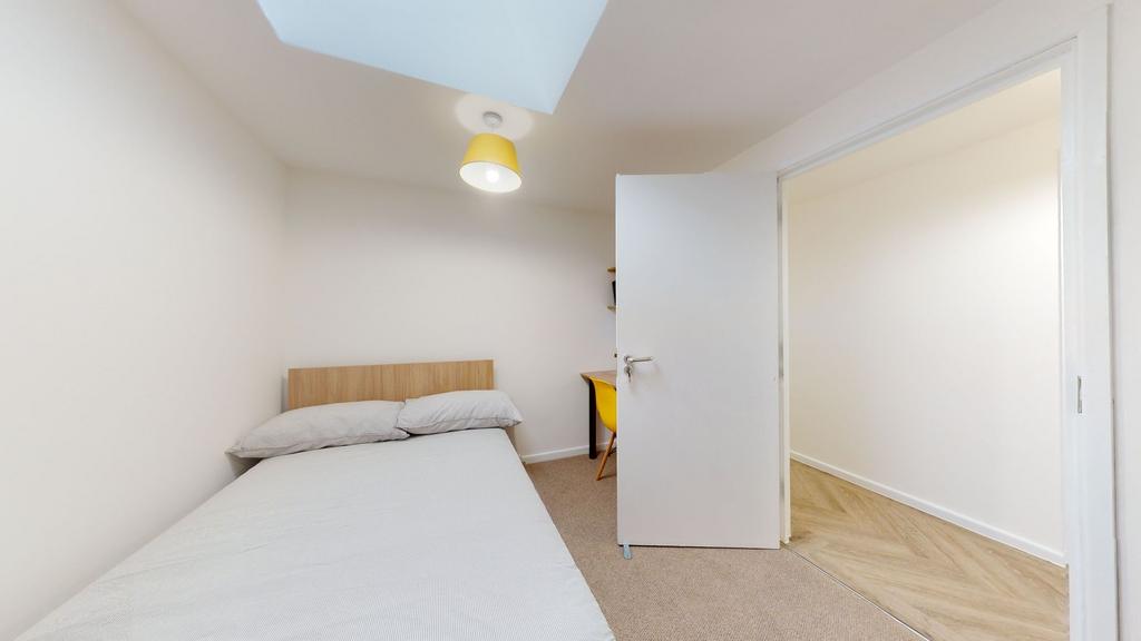 A bright, inviting single bedroom featuring a c...