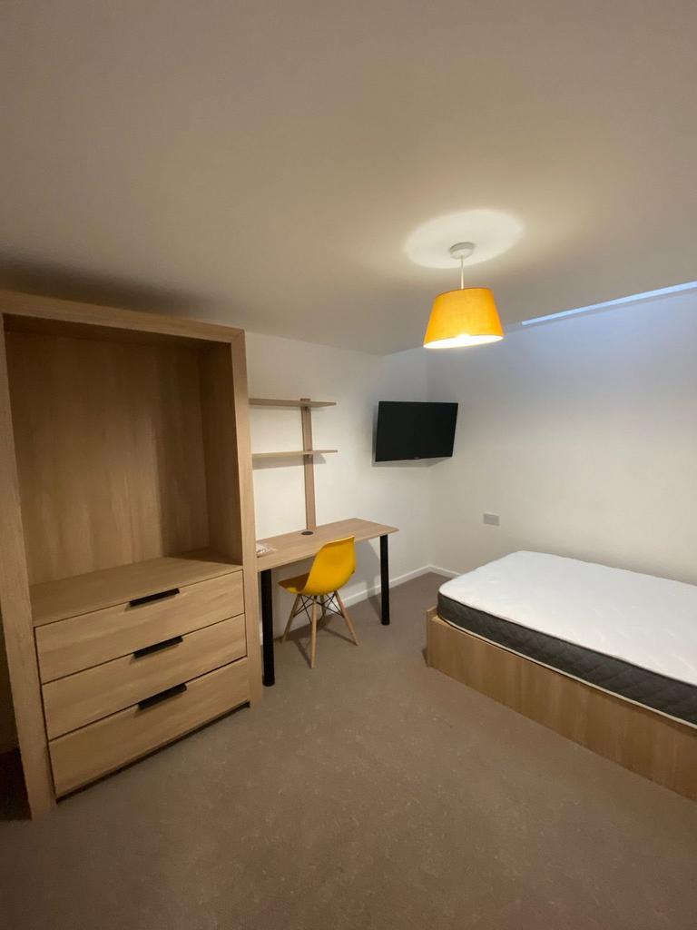 A cozy single bedroom featuring a wooden bed fr...