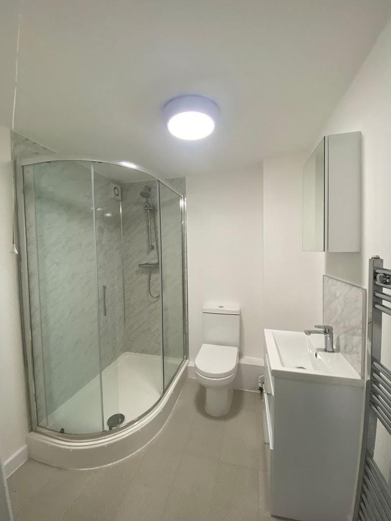Modern compact bathroom featuring a curved show...