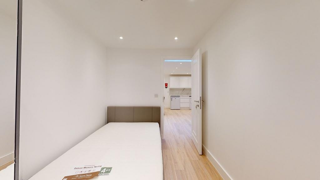A clean, minimalist single bedroom featuring a ...